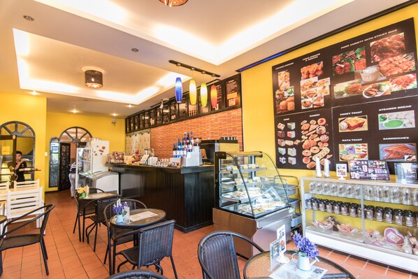 Ein Restaurantinneres mit Theke, Speisekartenanzeige, Sitzbereich und einer Vitrine.