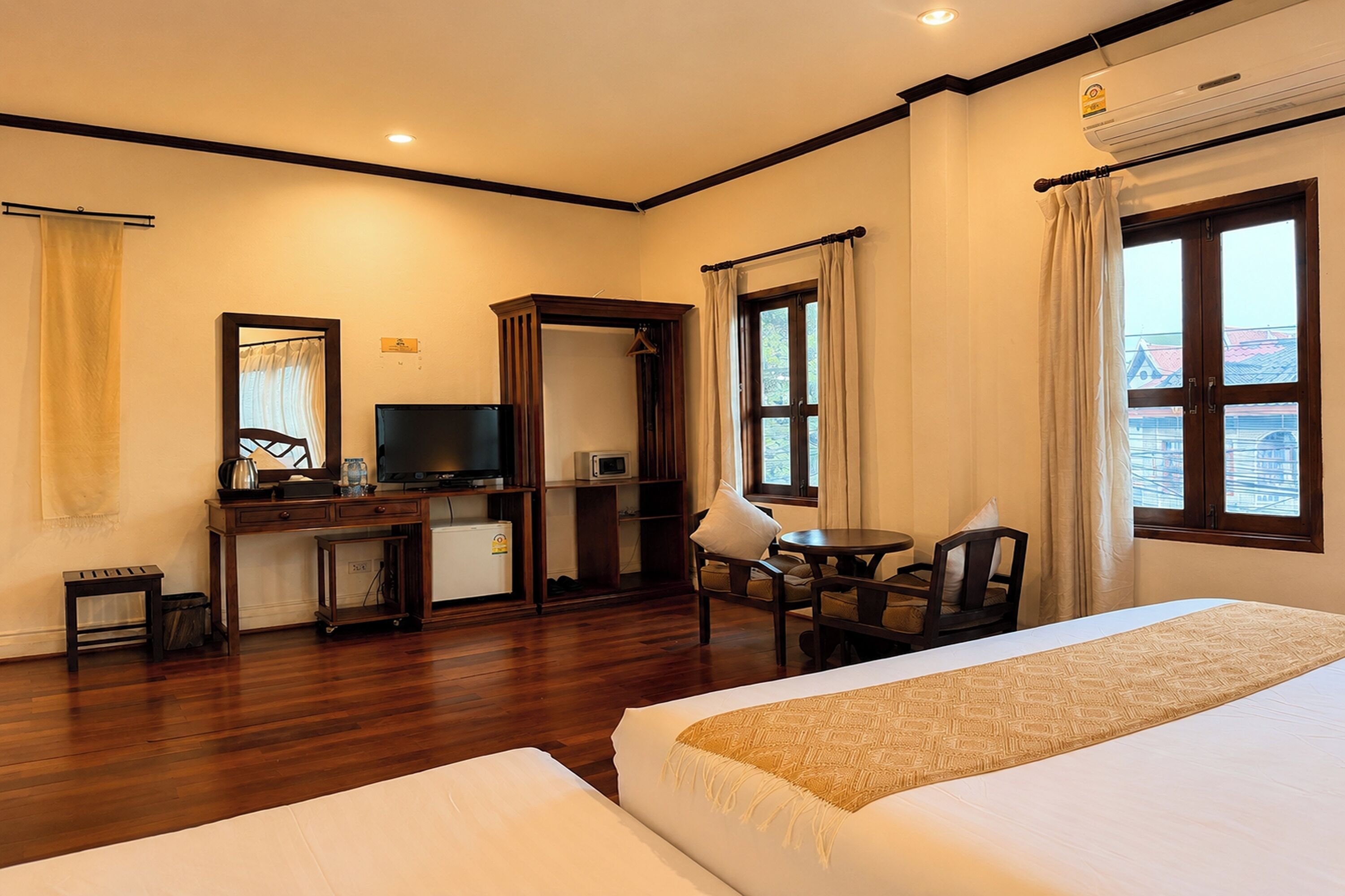 A hotel room with a bed, desk, television, and a view of buildings through the window.