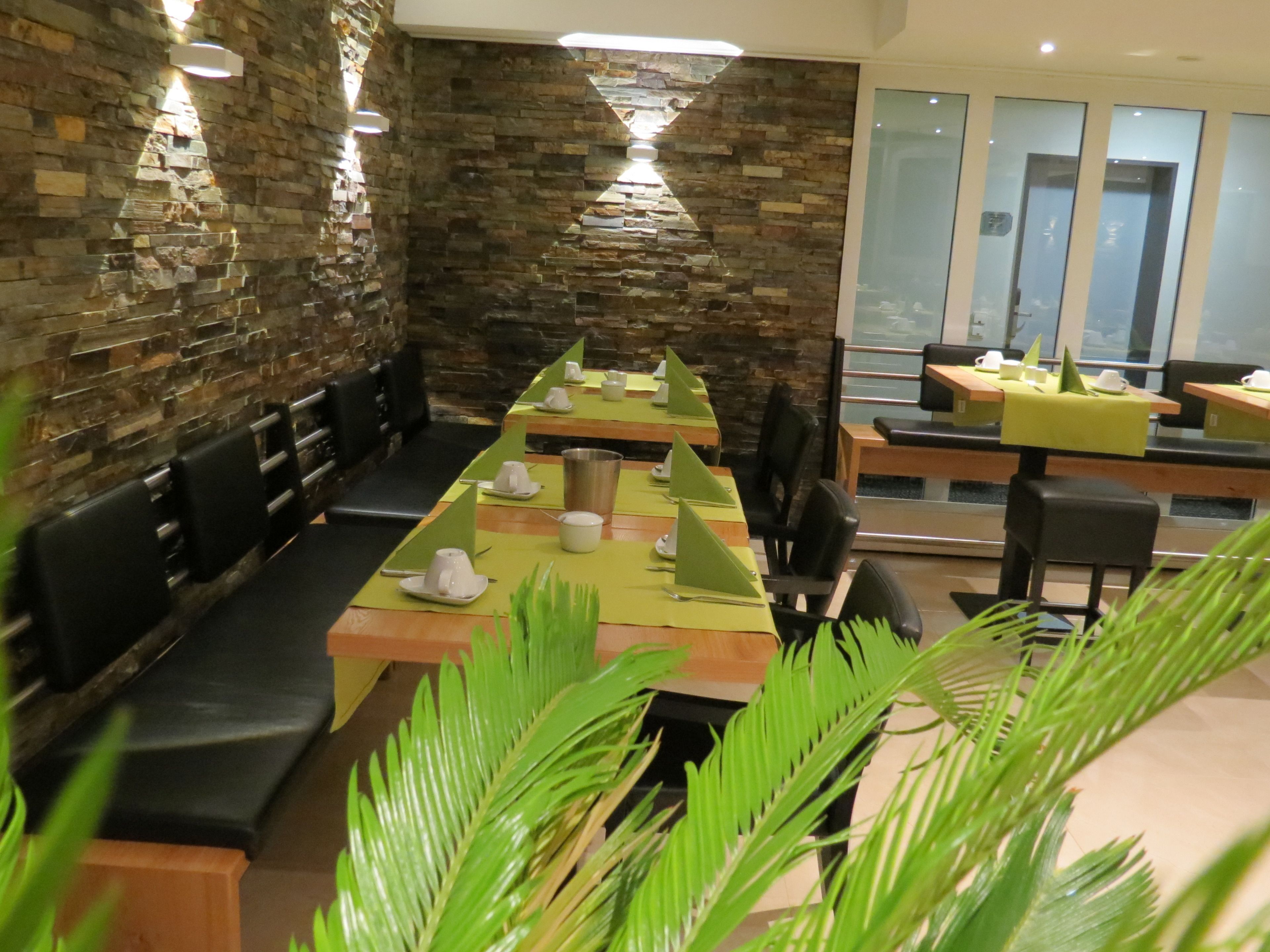 A restaurant with a long table set for dining, stone walls, and modern lighting.