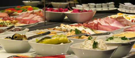 A buffet with various food items including meats, cheeses, and fruits.