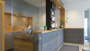 A reception area with a counter, wooden cabinets, a glass partition, and a potted plant. - Comfor Hotel Ulm City (Ulm)