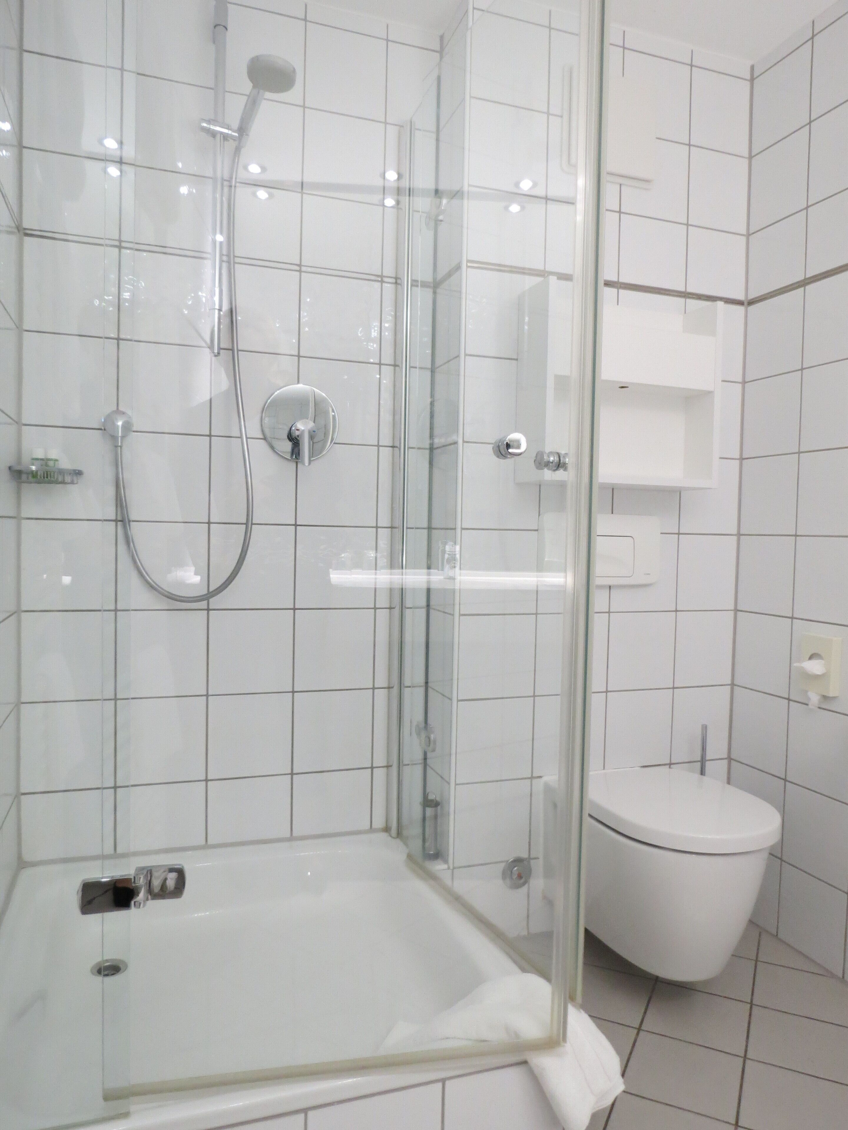 Un baño moderno con ducha de vidrio, inodoro blanco y bañera.