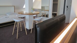 A modern hotel room with a bed, a round table with chairs, a TV, and a wardrobe. - Comfor Hotel Ulm City (Ulm)