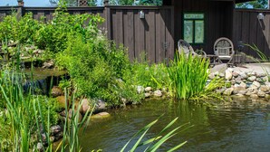 A wooden cabin with a pond, surrounded by lush greenery and rocks. - Lazy Cloud (Lake Geneva)