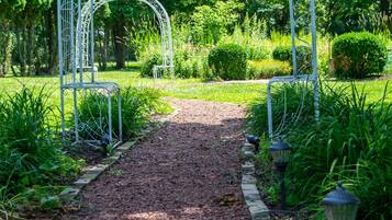 Un sentier de jardin agrémenté d’arceaux en métal et d’un chemin de gravier.