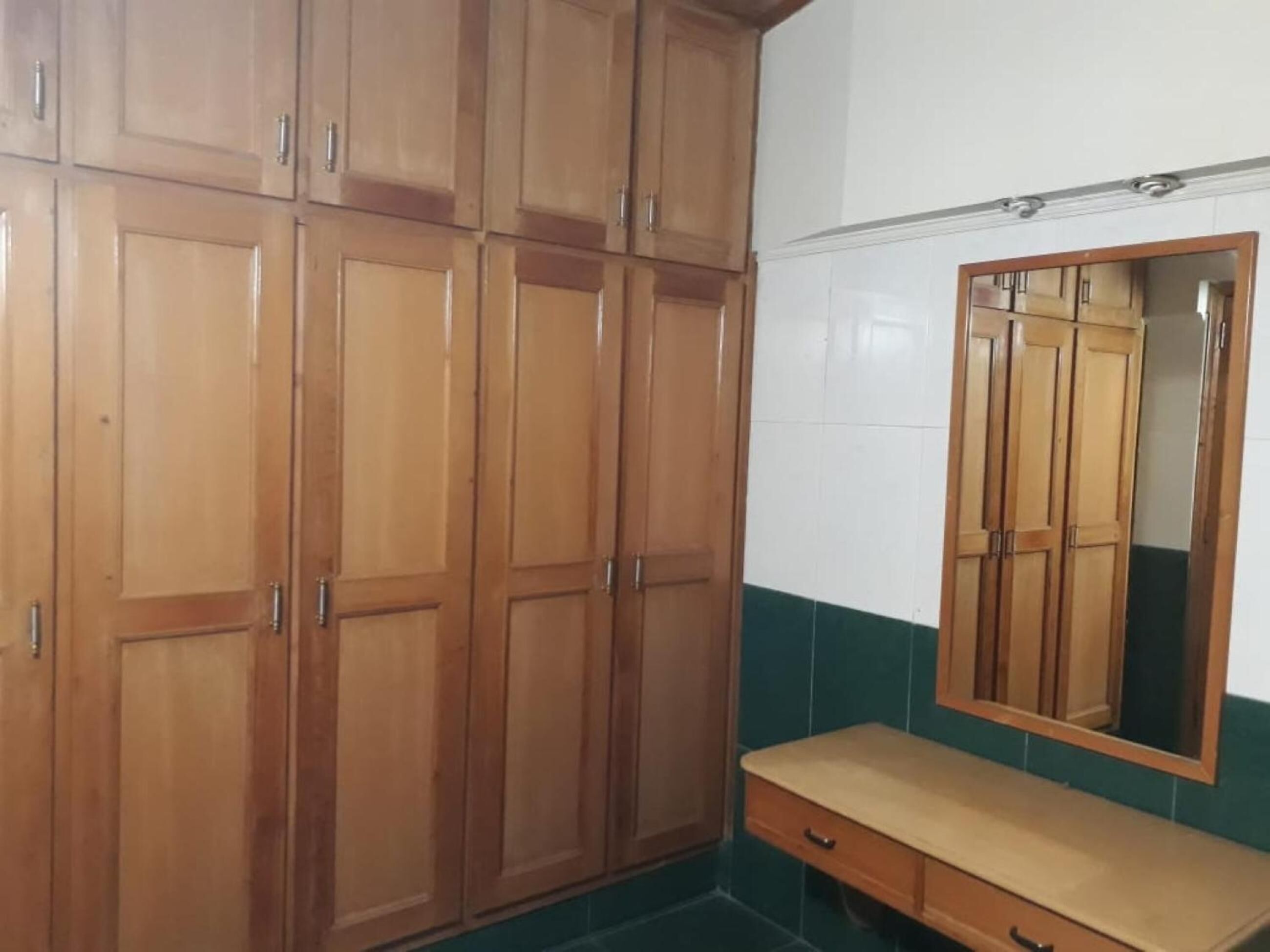 Una habitació amb armaris de fusta, un mirall i una panxa de fusta.