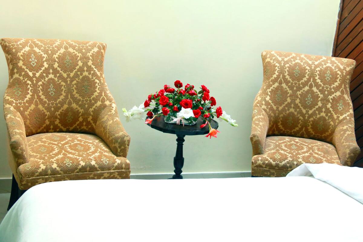 A room with two patterned armchairs and a small table with a floral arrangement.