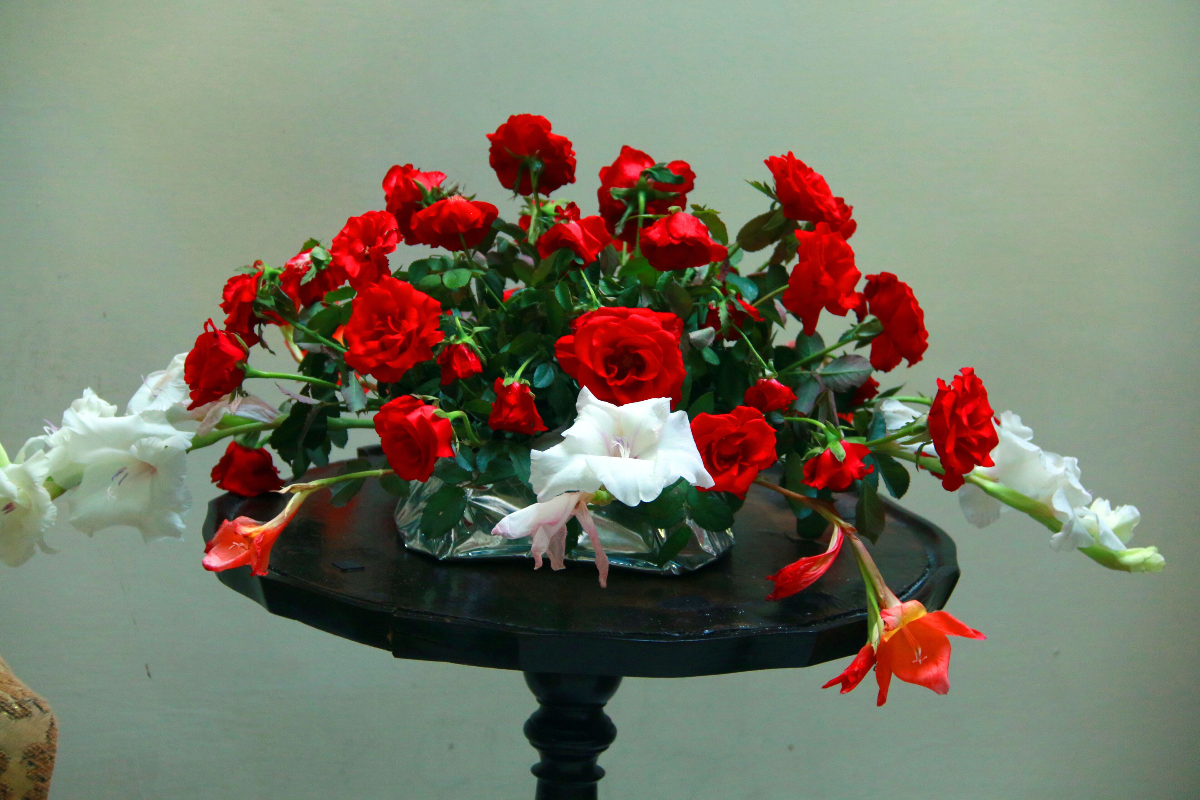 Un bouquet de roses rouges et blanches dans un vase transparent, posé sur une table noire.