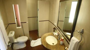 Un baño con inodoro, lavamanos, espejo y ducha.