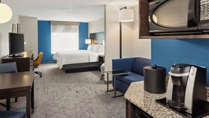 A hotel room with a bed, a desk, a chair, a coffee maker, and a microwave.