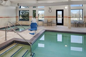 A pool area with a clear view of the pool, a blue chair, and a clock on the wall. - Holiday Inn Express Moline - Quad Cities Area by IHG (Moline)