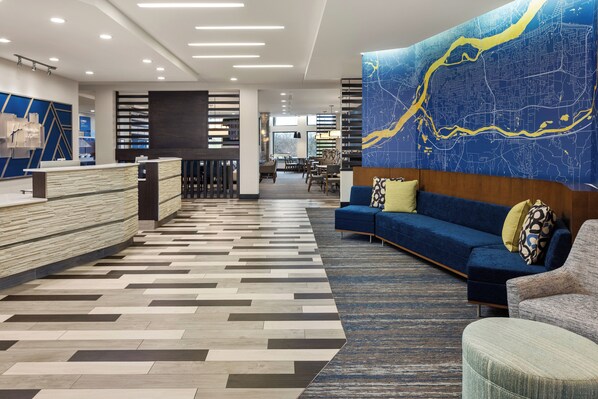 A modern hotel lobby with a reception desk, seating area, and a large map mural. - Holiday Inn Express Moline - Quad Cities Area by IHG (Moline)