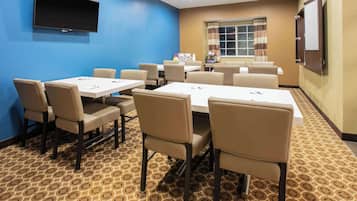 A conference room with a blue wall, a flat-screen TV, and a patterned carpet.