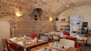 Un restaurante con paredes de piedra, mesas de madera y sillas rojas.