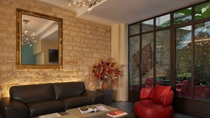 Una sala de estar moderna con una pared de piedra, un espejo grande, un sofá de cuero, una silla roja y una mesa de centro con revistas.