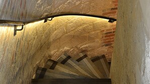 Una escalera con un muro de piedra a un lado y una barandilla de metal.