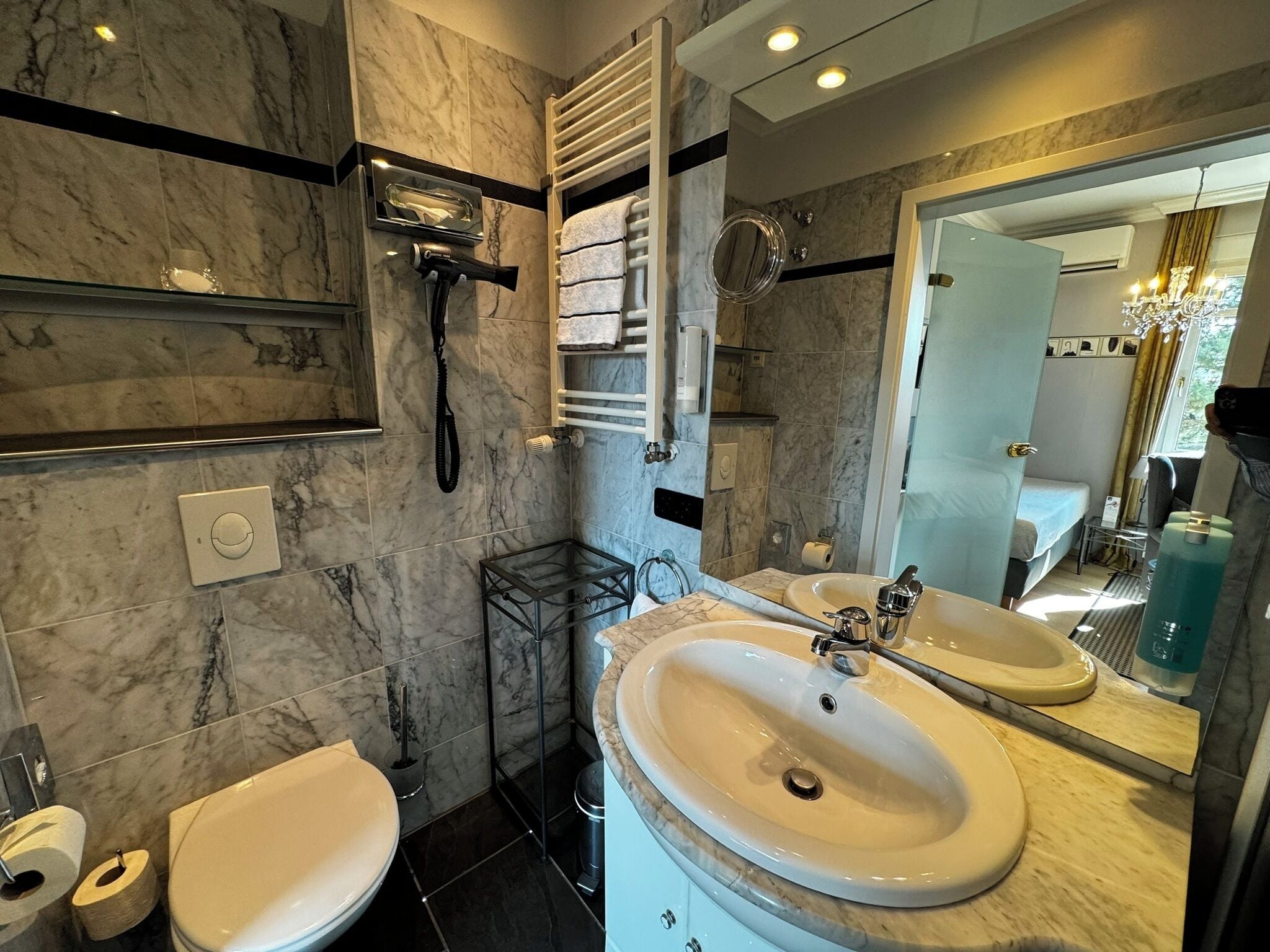 Une salle de bain moderne avec un sol en marbre, deux lavabos, une douche et un grand miroir.