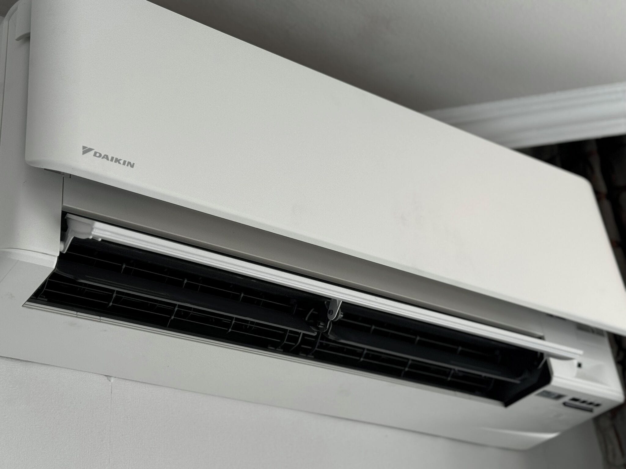 Valkoinen Daikin-ilmastointilaite, joka on asennettu seinään.