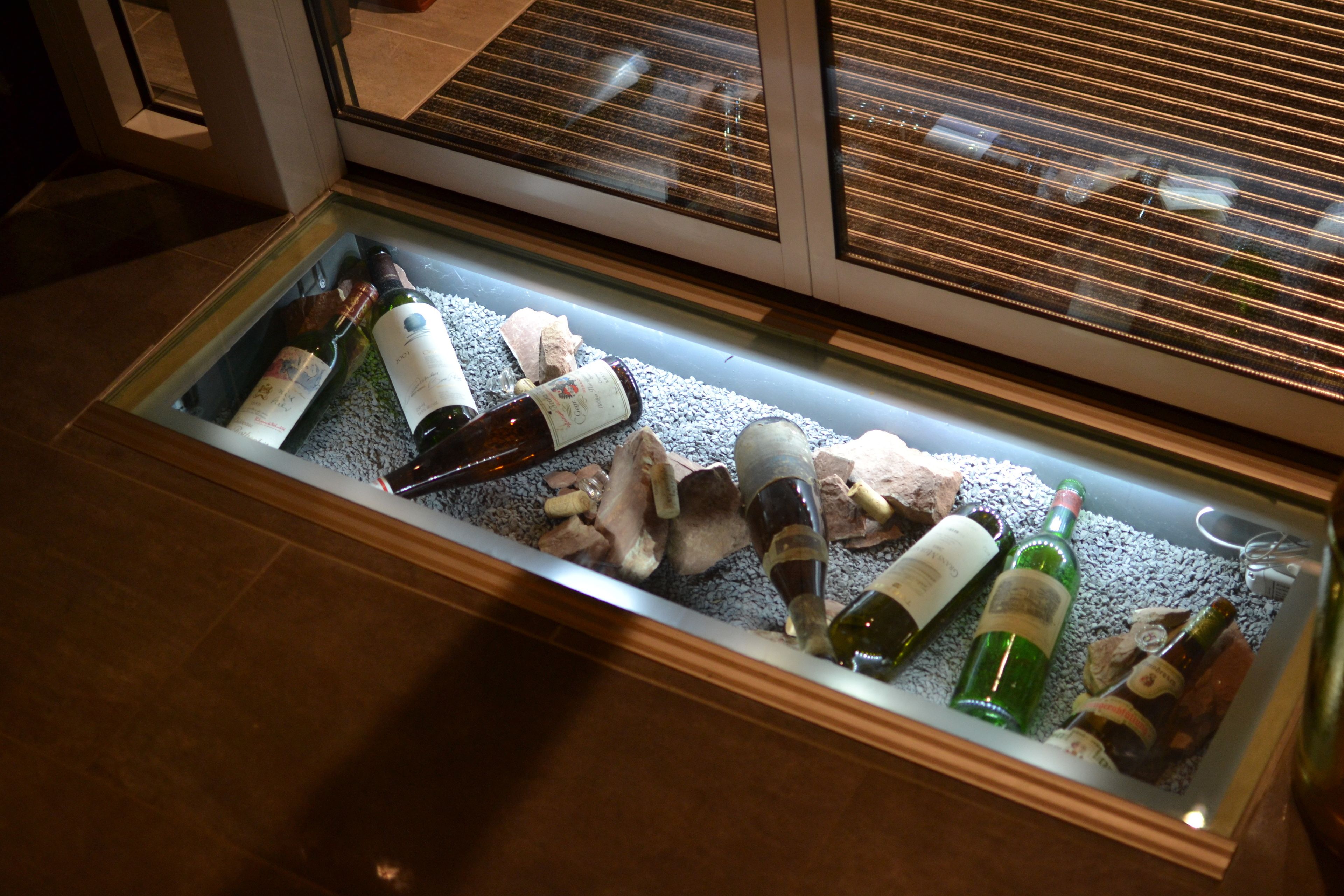 Una vitrina con varias botellas de vino y champán, algunas con corchos, sobre una cama de hielo.