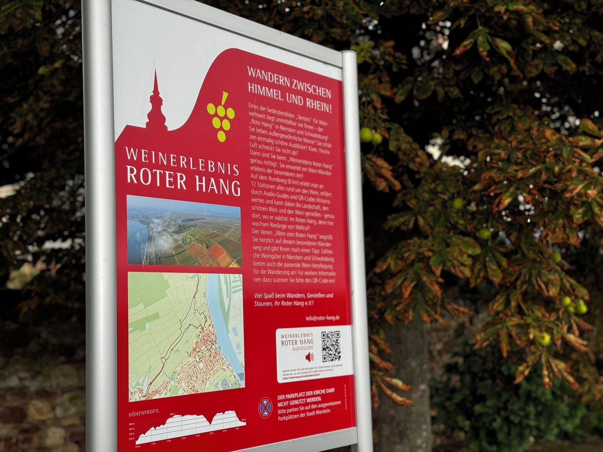 Een bord met tekst en een kaart, waarschijnlijk met informatie over een wandelpad of gebied.