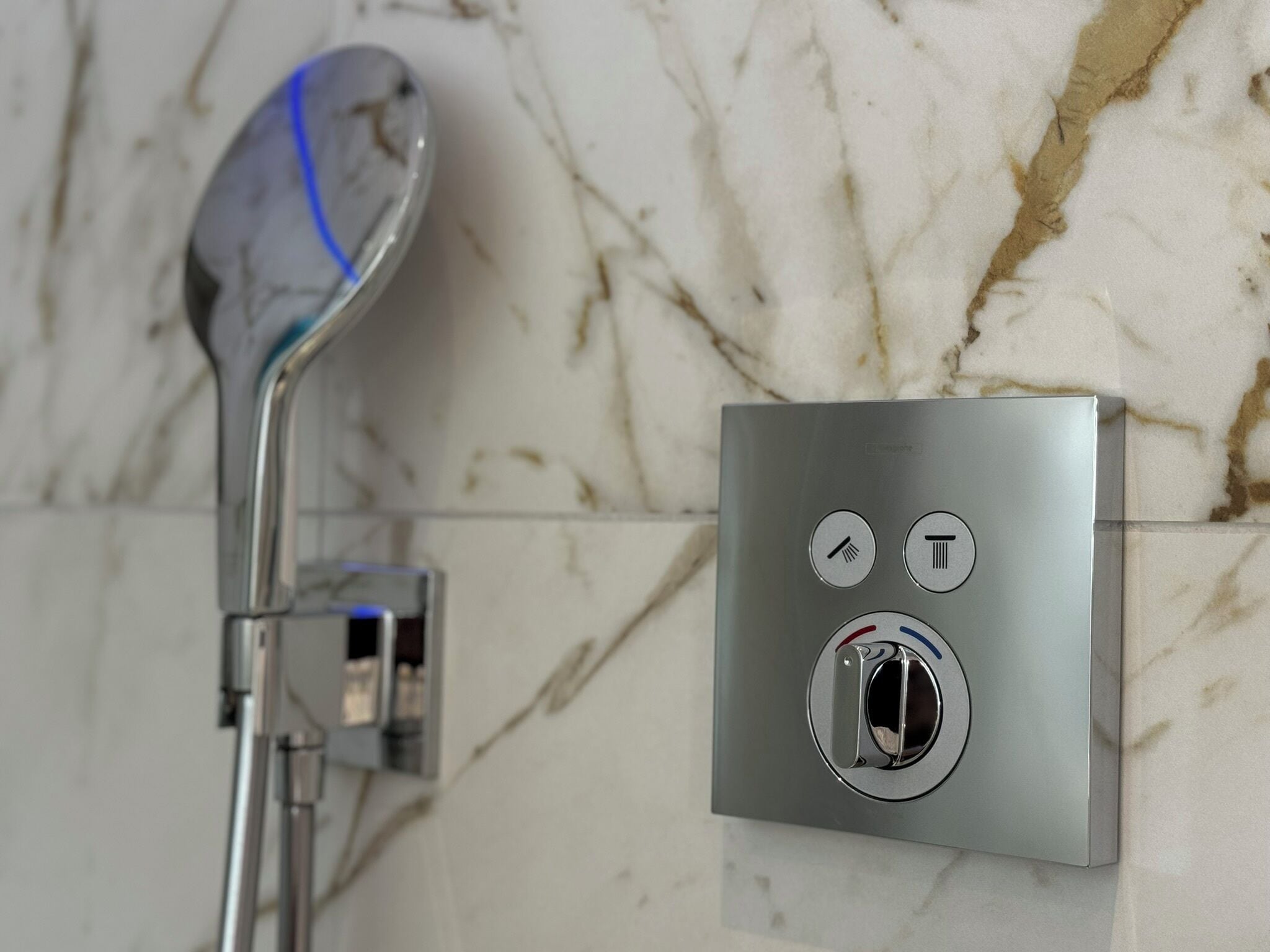 Ein modernes Badezimmer mit einer wandmontierten Duschsteuerung und einer Handbrause.
