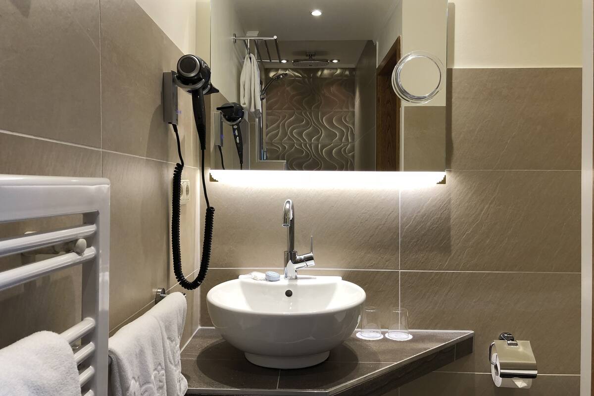A bathroom with a white sink, a towel rack, a hairdryer, and a mirror.