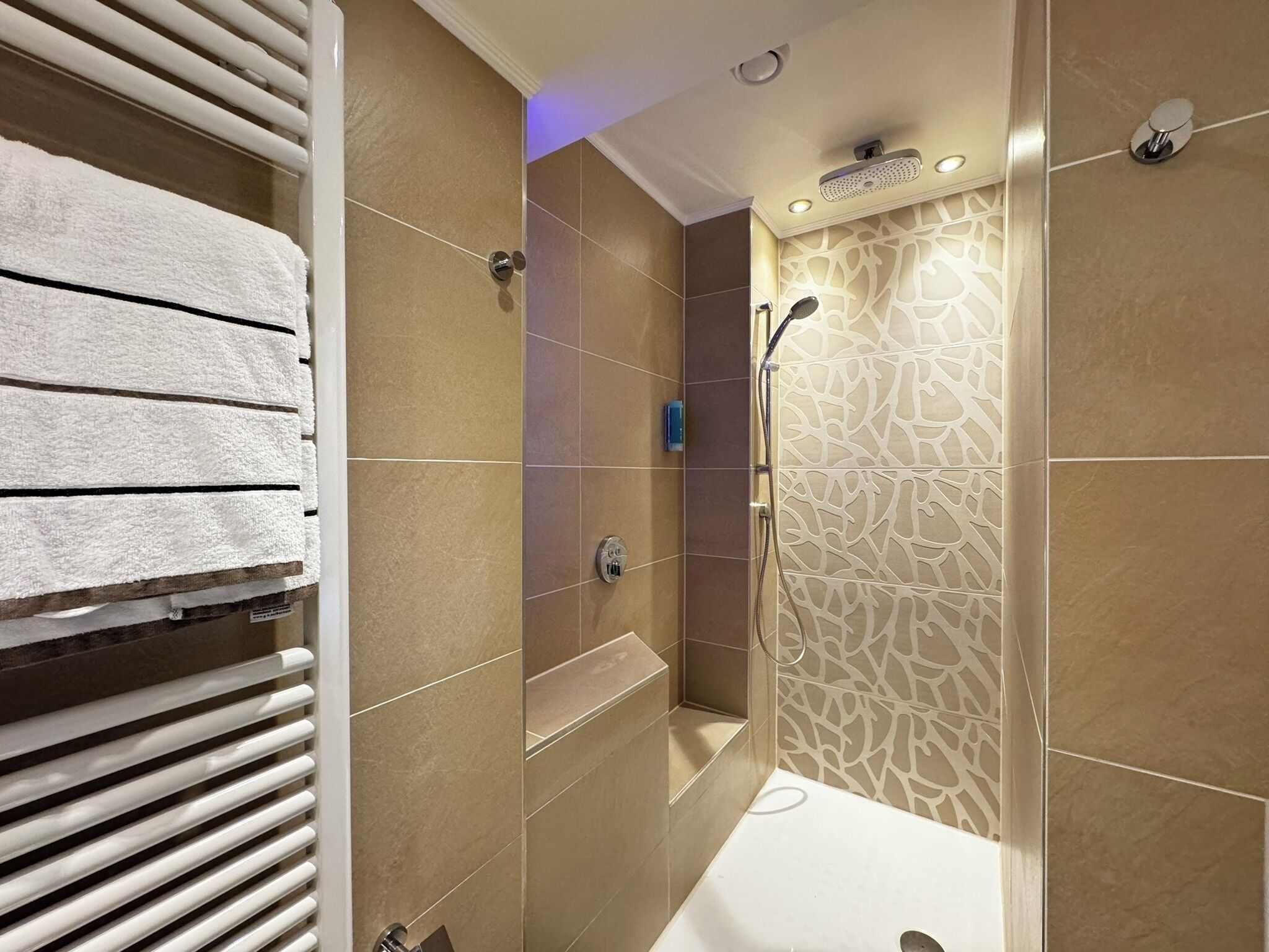 A modern bathroom with a shower, a bathtub, and a towel rack.
