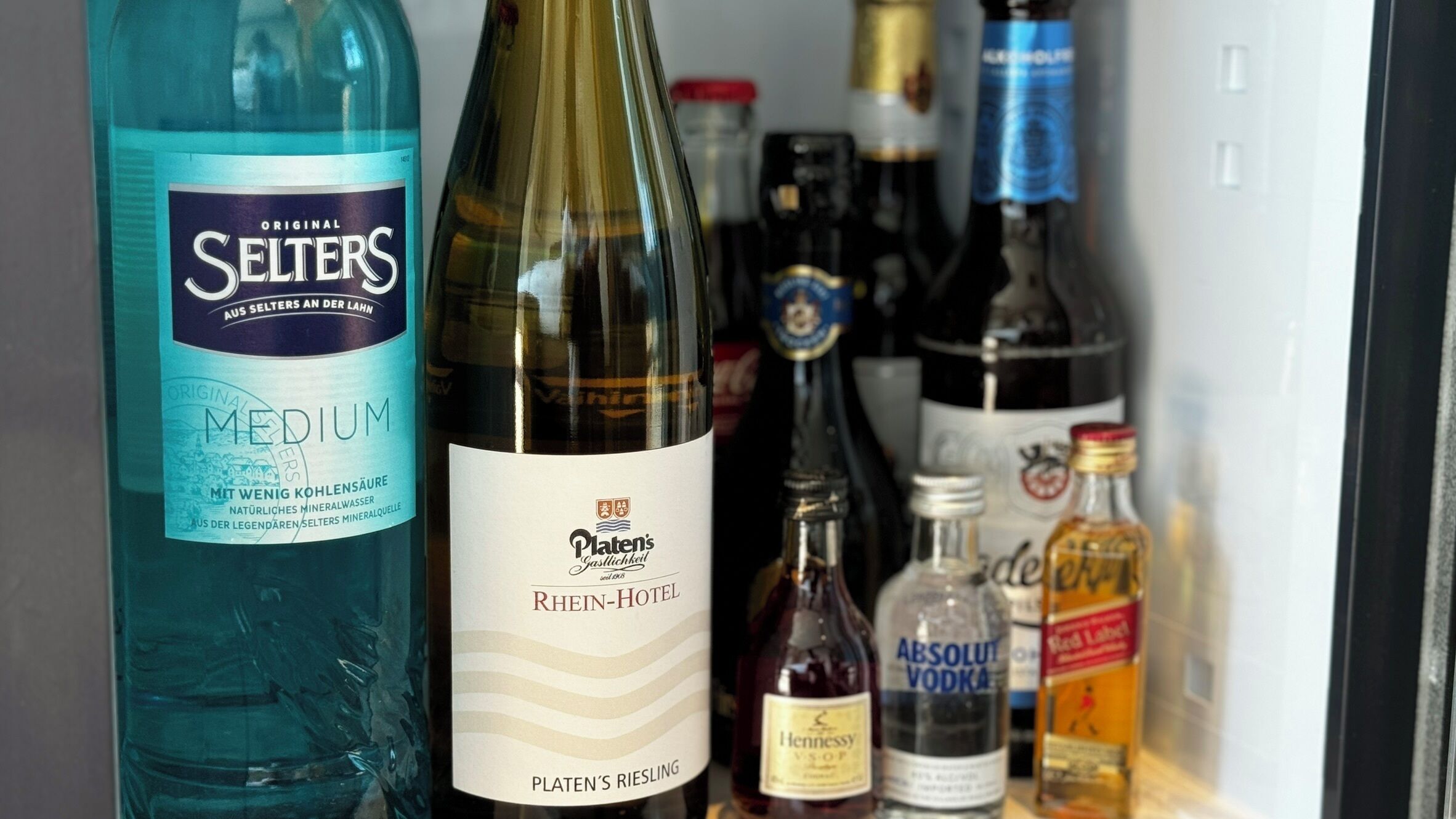 A refrigerator containing various bottles including Medium, Platen's Riesling, Absolut Vodka, and Red Label.
