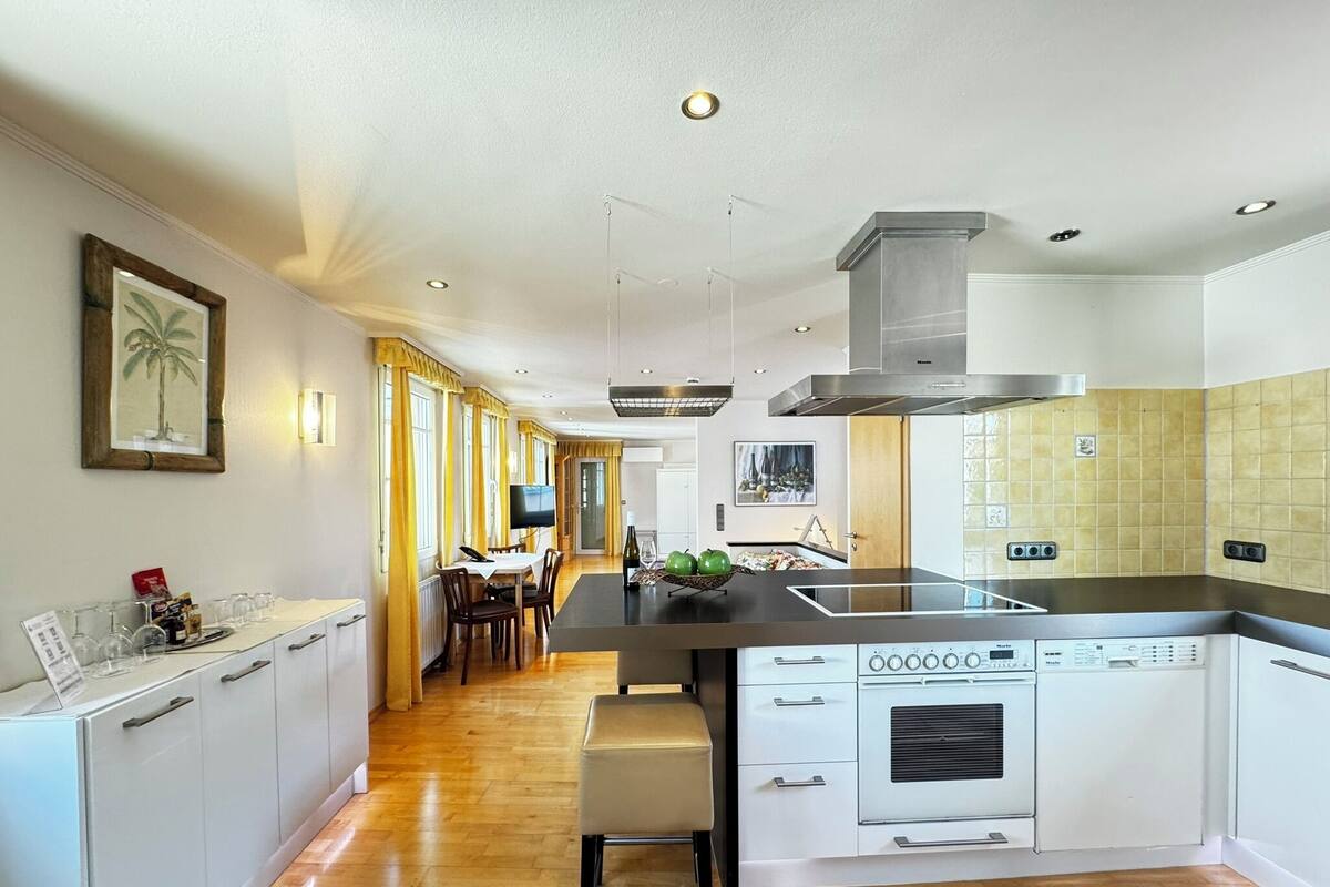 A modern kitchen with a central island, white cabinetry, and a built-in dishwasher.