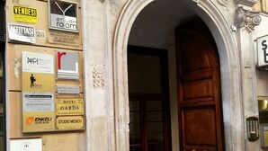 A building entrance with a large wooden door and an ornate stone archway. - DG Prestige Room (Rome)