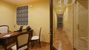 A conference room with a wooden table, chairs, a laptop, and a patterned wall hanging. - DG Prestige Room (Rome)
