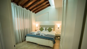 A hotel room with a large bed, two bedside lamps, a headboard, and a wooden ceiling. - Myroandrou Beach Apartments (Paralimni)