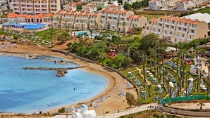 A coastal resort with a beach, a pool, and a church. - Myroandrou Beach Apartments (Paralimni)