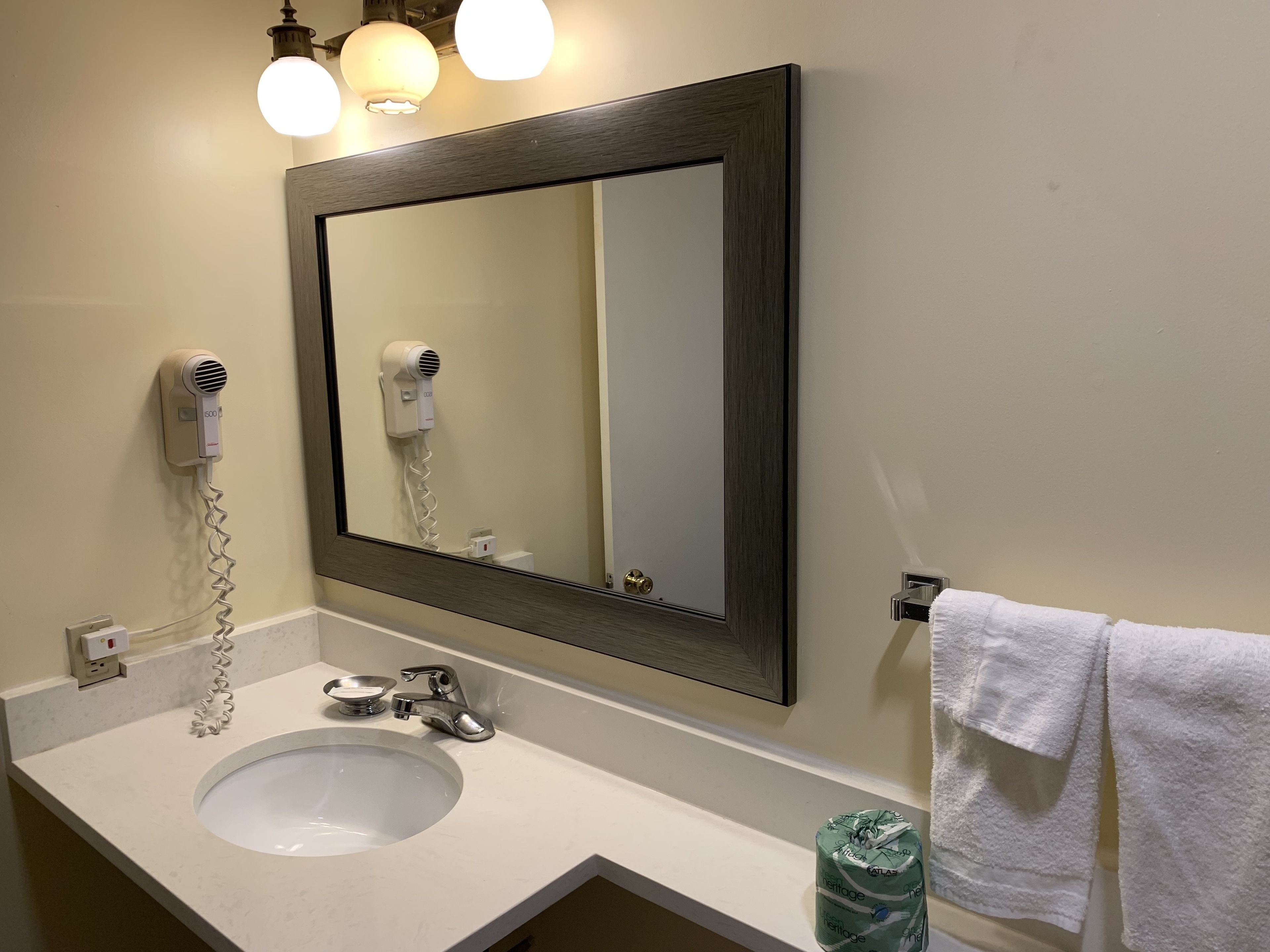 A bathroom with a white sink, a mirror, a hairdryer, and a towel rack.