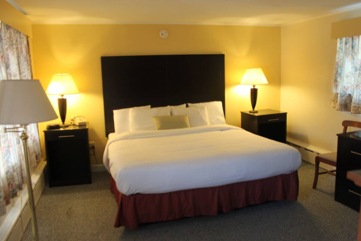 A hotel room with a large bed, two bedside tables, a desk, and a chair.