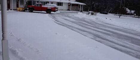 A two-story house with a snow-covered driveway and a red truck parked in front.