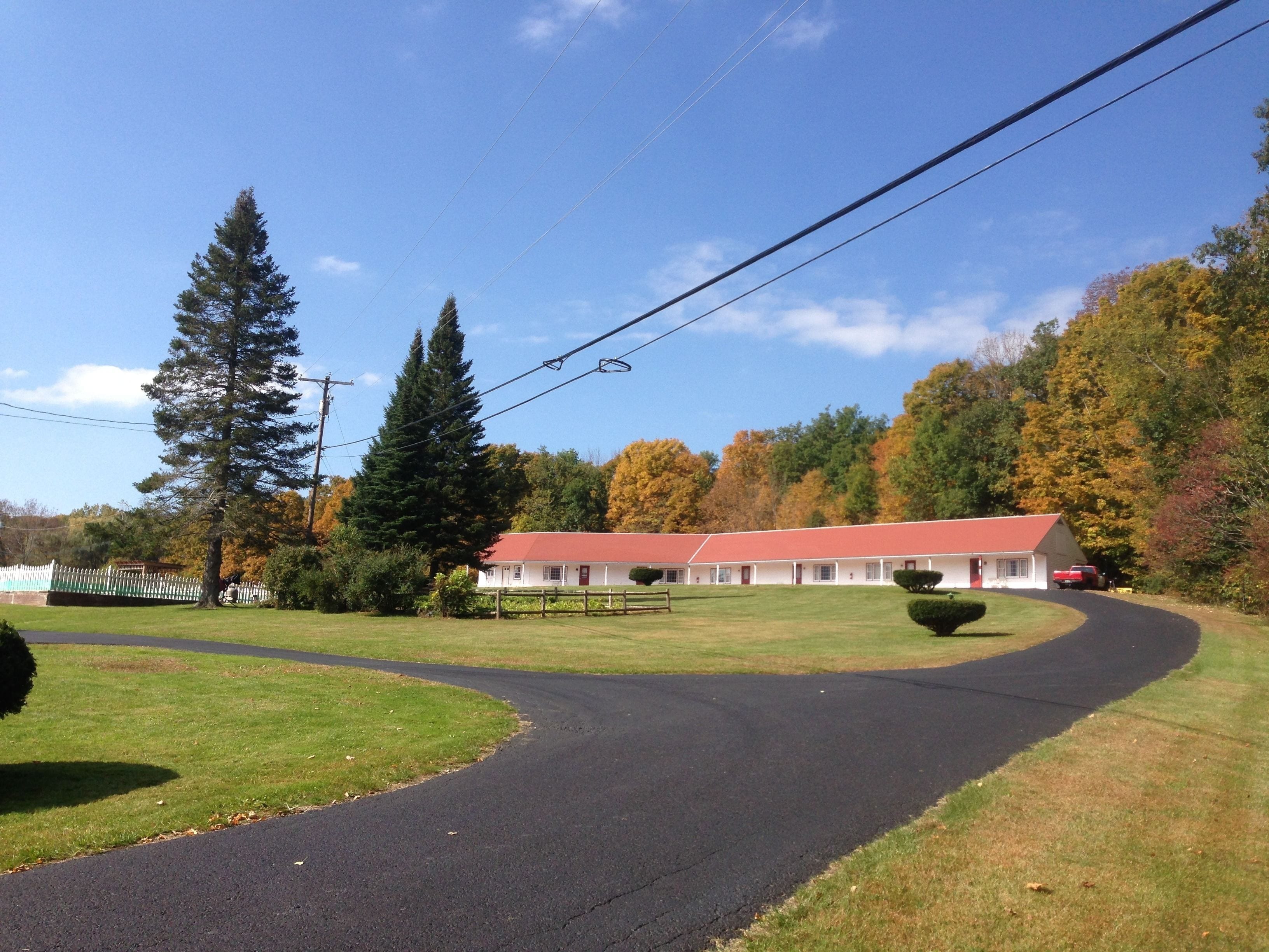 A two-story building with a red roof, surrounded by a well-maintained lawn and trees.