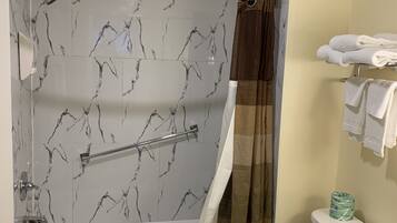 A bathroom with a bathtub, shower, toilet, and a towel rack.