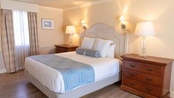 A neatly made bed with a blue and white striped blanket, two bedside tables with lamps, and a wooden nightstand with drawers.