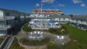 A hotel with a pool area, outdoor seating, and a flag. - Anchor In Distinctive Waterfront Lodging (Hyannis)