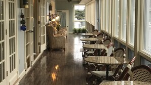 A corridor with wooden flooring, wicker furniture, and large windows. - Anchor In Distinctive Waterfront Lodging (Hyannis)