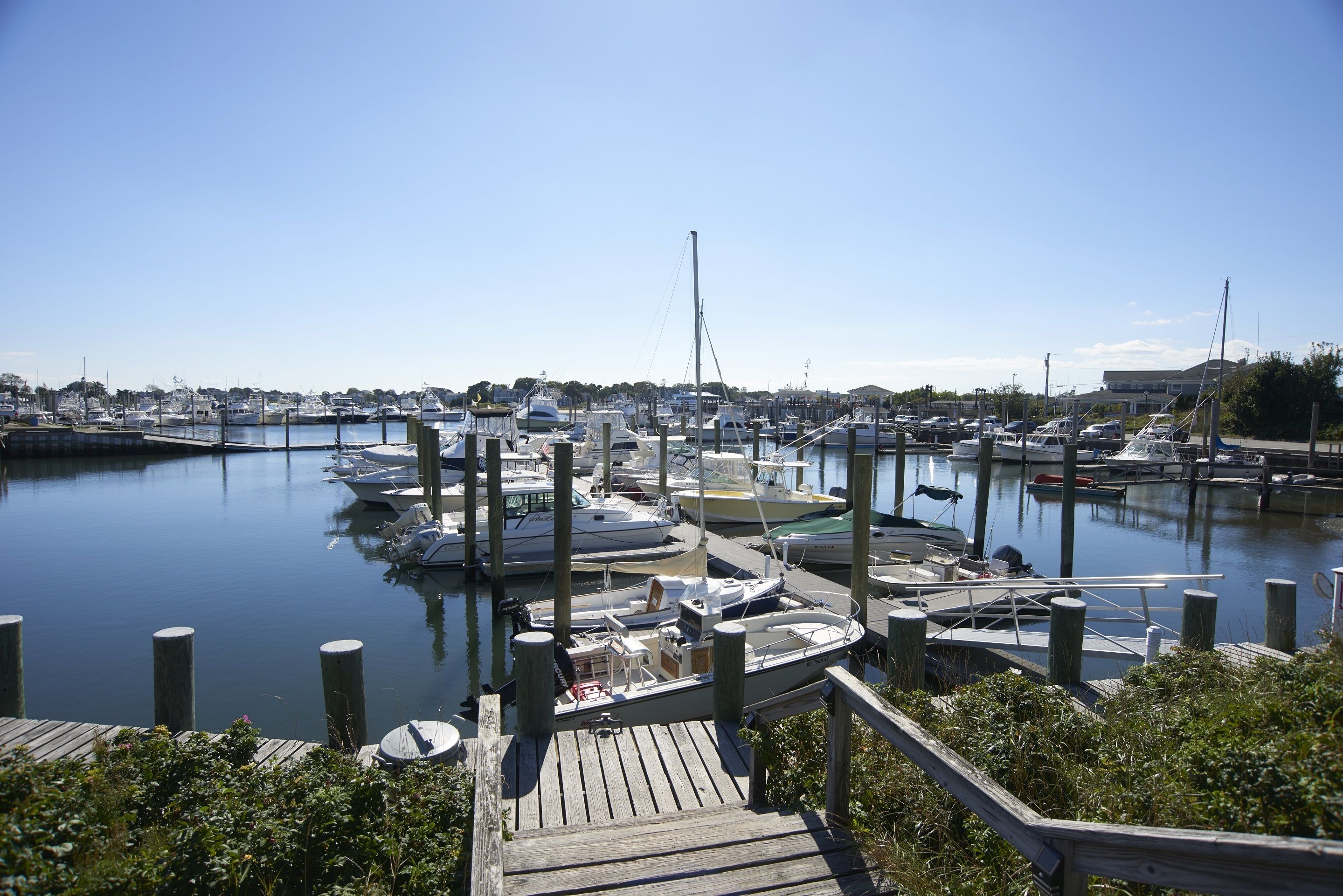 A marina with boats docked at wooden piers, surrounded by calm water and clear skies.