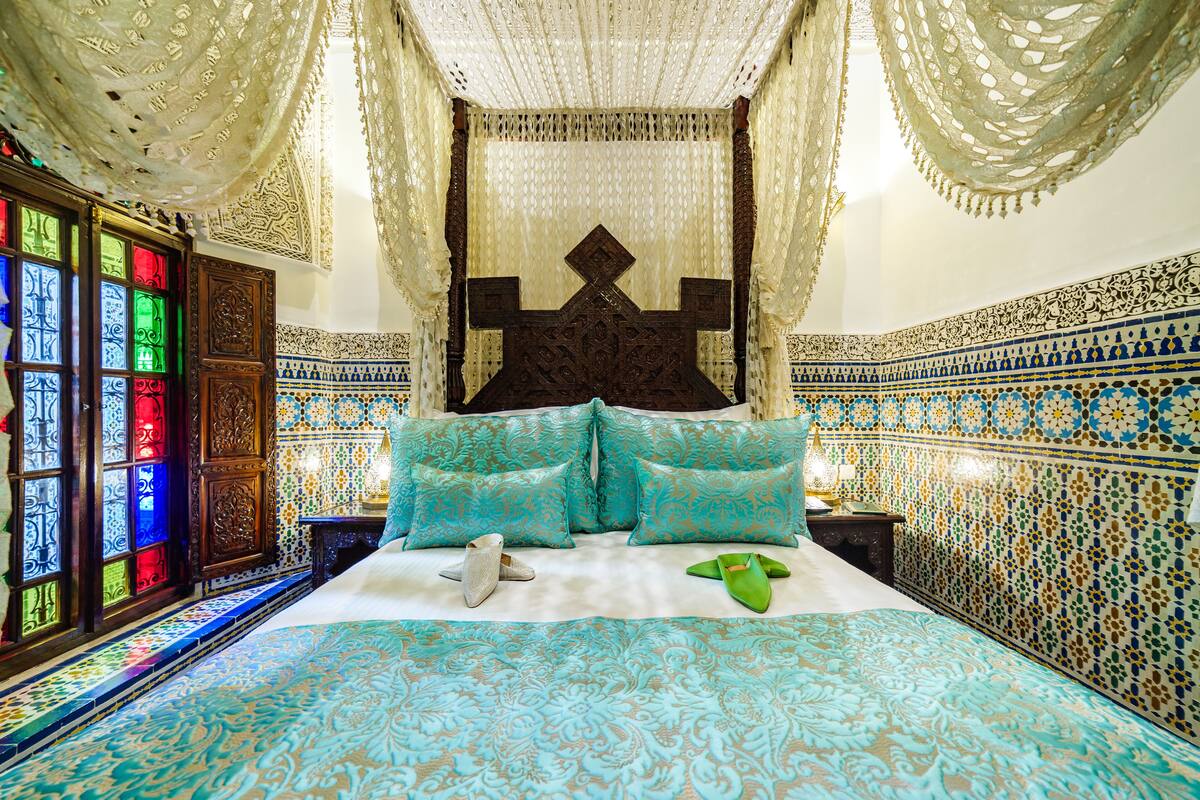 A room with a large bed, ornate curtains, and patterned walls.