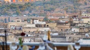 Vista de un paisaje urbano con una mesa lista para comer, con vistas a edificios y una colina con árboles.