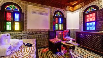 Quarto com trabalhos detalhados em azulejos, piso xadrez e cama com toalhas.