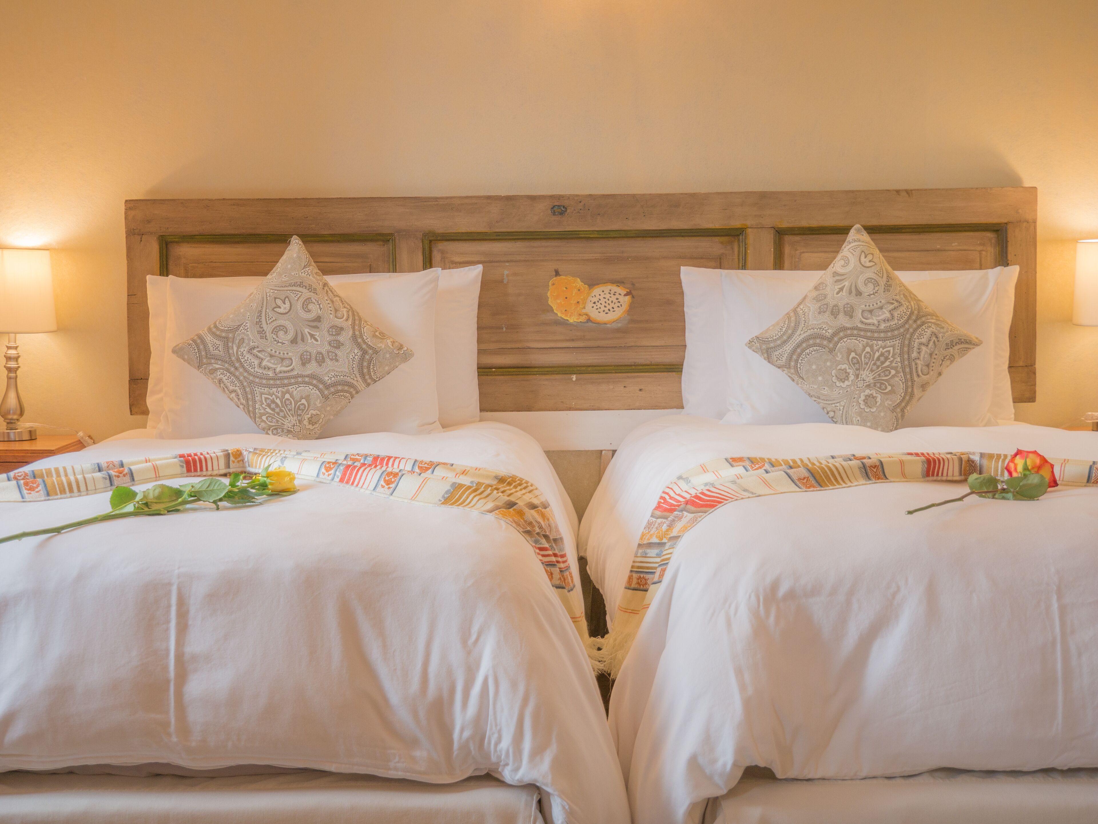 A double room with two beds, each with a patterned bedspread and decorative pillows.
