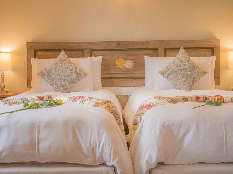 A double room with two beds, each with a patterned bedspread and decorative pillows.