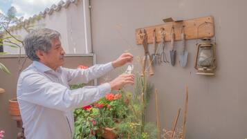 A man tending to plants in a garden area with various gardening tools and pots.