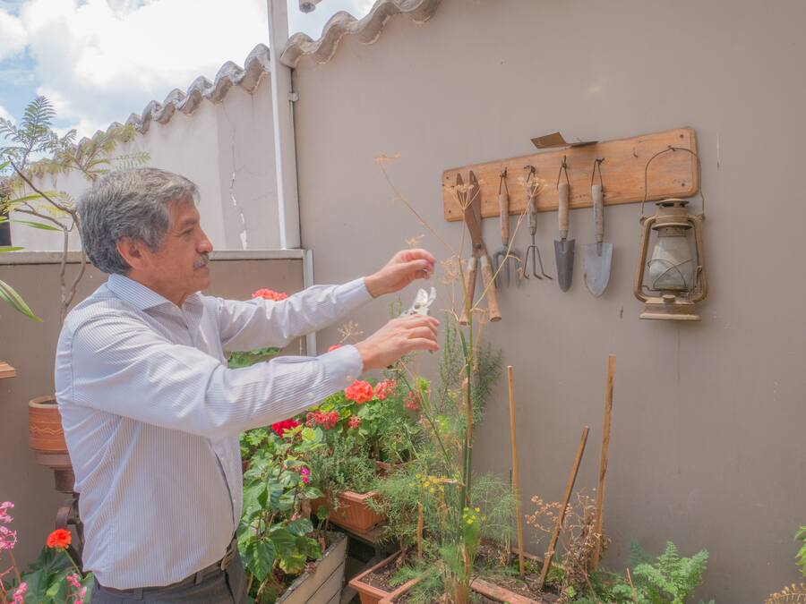 A man tending to plants in a garden area with various gardening tools and pots.
