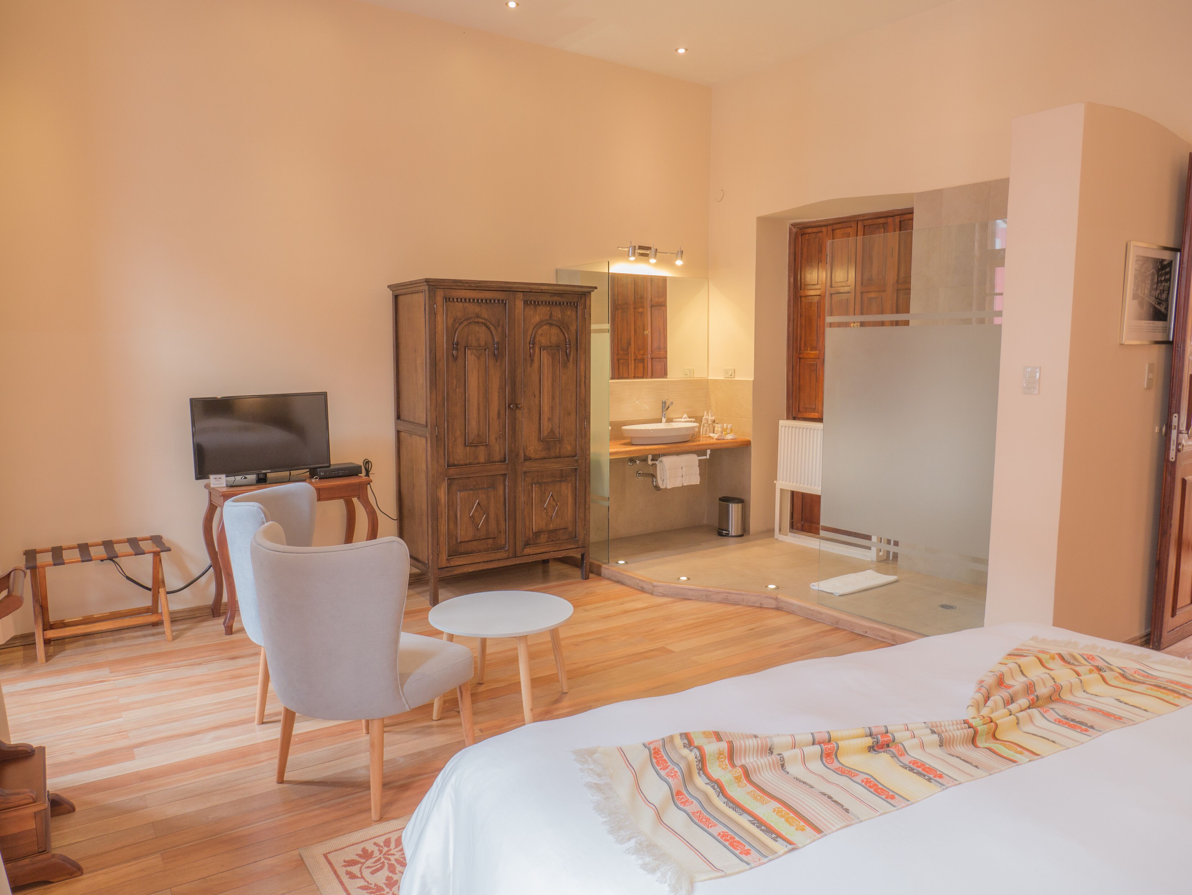 Une chambre d’hôtel comprenant un lit, une télévision, une armoire, une salle de bain et un petit coin salon.